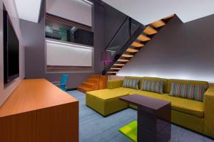a living room with a couch and a staircase at Aloft Kuala Lumpur Sentral in Kuala Lumpur