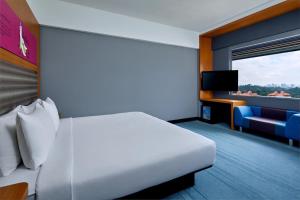 a hotel room with a white bed and a television at Aloft Kuala Lumpur Sentral in Kuala Lumpur