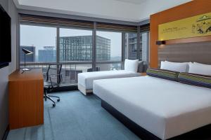 a hotel room with two beds and a desk and a window at Aloft Kuala Lumpur Sentral in Kuala Lumpur