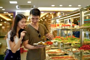 a man and a woman standing in a store with a plate of food at Aloft Kuala Lumpur Sentral in Kuala Lumpur