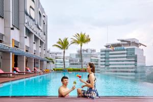 a woman and a child sitting next to a swimming pool at Aloft Kuala Lumpur Sentral in Kuala Lumpur