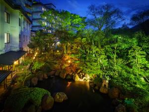 a pond in a garden at night with lights at Hotel Hoho "A hotel overlooking the Echigo Plain and the Yahiko mountain range" formerly Hotel Oohashi Yakata-no-Yu in Niigata
