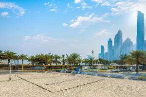 a beach with palm trees and a city in the background at Al Habtoor Grand Resort, Autograph Collection in Dubai