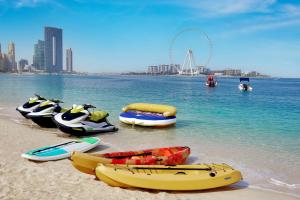 a group of boats on the beach with a city in the background at Al Habtoor Grand Resort, Autograph Collection in Dubai