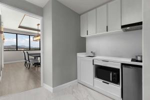 a kitchen with white cabinets and a dining room with a table at Courtyard by Marriott Phuket Town in Phuket Town
