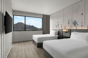 a hotel room with two beds and a large window at Courtyard by Marriott Phuket Town in Phuket Town
