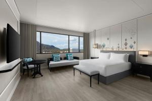 a bedroom with a bed and a desk and a tv at Courtyard by Marriott Phuket Town in Phuket Town