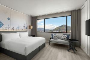 a bedroom with a bed and a chair and a window at Courtyard by Marriott Phuket Town in Phuket Town