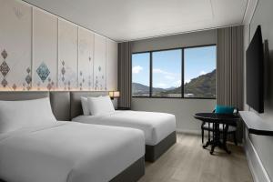 a hotel room with two beds and a window at Courtyard by Marriott Phuket Town in Phuket Town