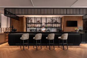 a woman standing behind a bar with four stools at Courtyard by Marriott Phuket Town in Phuket Town