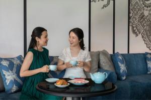 two women sitting around a coffee table with tea cups at Courtyard by Marriott Phuket Town in Phuket Town