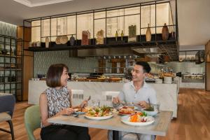 a man and woman sitting at a table eating food at Courtyard by Marriott Phuket Town in Phuket Town