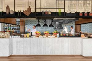 two chefs preparing food behind a counter in a kitchen at Courtyard by Marriott Phuket Town in Phuket Town