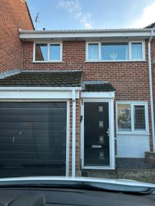 Un garaje con puerta negra y una casa de ladrillo. en Spacious 3BR Home in Colchester, with Private Parking, en Colchester