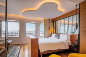 a bedroom with a bed and a desk and windows at Renaissance Paris Republique Hotel & Spa in Paris