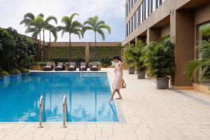 a woman walking next to a swimming pool at Courtyard by Marriott Pune Chakan in Pune