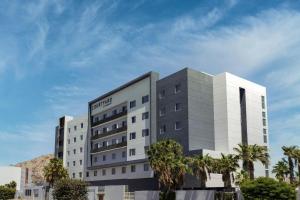 a large white building with palm trees in front of it at Courtyard by Marriott Hermosillo in Hermosillo