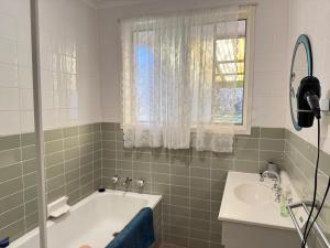 キャンベラにあるScullin 3BR Houseの浴槽と洗面台と窓のあるバスルーム +17枚の写真