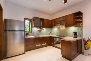 a kitchen with wooden cabinets and a stainless steel refrigerator at Villa Green Manggo Seminyak Bali in Seminyak
