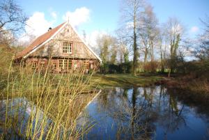 un granero junto a un río con un reflejo en el agua en B&B De Hagmolenbeek Boekelo, en Boekelo