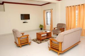 a living room with two chairs and a tv at Holidayincoorg Orchid Villa in Madikeri