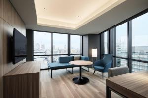 un soggiorno con tavolo, sedie e finestre di Courtyard by Marriott Osaka Honmachi ad Osaka