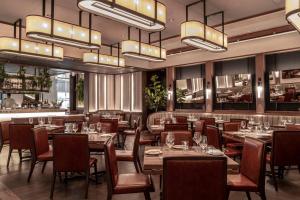 a restaurant with tables and chairs and chandeliers at Bvlgari Hotel London in London