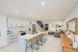a kitchen and living room with white cabinets and bar stools at Central Modern Spacous Townhouse 290B in Temora