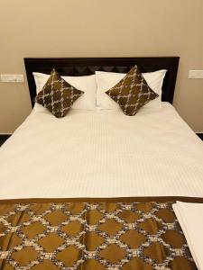 un letto con lenzuola e cuscini marroni e bianchi di The Forest Grove by Living Circle a Yelagiri