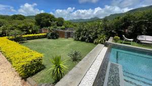 une arrière-cour avec une piscine et un jardin dans l'établissement Un Havre de Paix Entre Mer et Montagne à L'ile Maurice!, à Petite Case Noyale