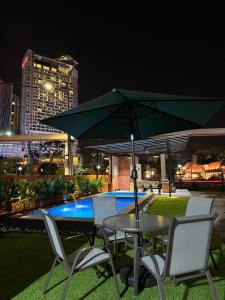 a table and chairs with an umbrella next to a pool at MARI Suites in Malacca