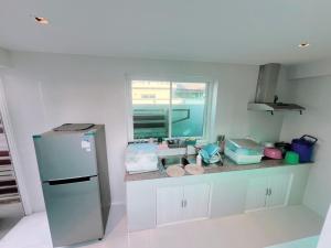 a kitchen with a counter with a refrigerator and a window at บ้านบลูสกาย POOL VILLA Cha-am in Cha Am