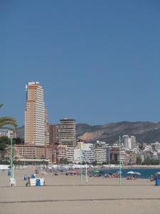 a beach scene with a large building and people on the beach at Apartamentos Beni-Beach in Benidorm