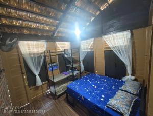 a bedroom with a bed with a blue comforter at Tein homestay in Rengit