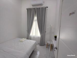 a white bedroom with a bed and a window at Ivory Damai Nature Homestay in Parit Raja