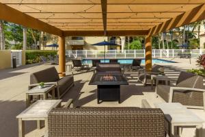 a patio with chairs and a table and a pool at Courtyard by Marriott Fort Lauderdale North/Cypress Creek in Fort Lauderdale