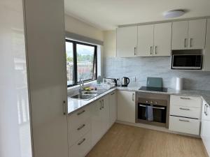 una cucina con mobili bianchi e un lavandino di The White House a Tokoroa