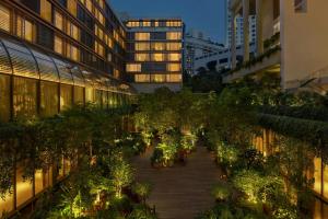 um corredor em um prédio com árvores e luzes em The Singapore EDITION em Singapura