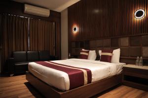 a bedroom with a large bed and a chair at Vivotel Hotel Surat in Surat