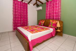 a bedroom with a bed with a pink and white blanket at Bienvenue Au Tropic Venucia in Port-Louis