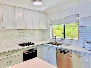 a kitchen with white cabinets and a sink and a window at Perfect Oceanfront Cottesloe apartment in Perth +12 photos