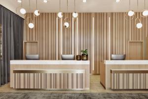 a lobby with two reception desks and pendant lights at Courtyard by Marriott Munich City East in Munich