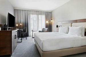 a hotel room with a bed and a desk with a television at Courtyard by Marriott Munich City East in Munich