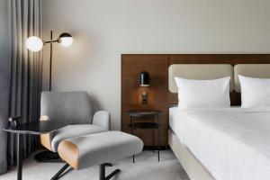 a bedroom with a bed and a chair and a desk at Courtyard by Marriott Munich City East in Munich