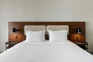 a bed with two white pillows and two chairs at Courtyard by Marriott Munich City East in Munich