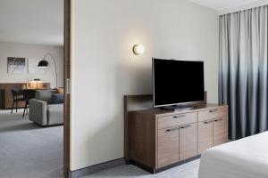 a hotel room with a television on a dresser with a bedroom at Courtyard by Marriott Munich City East in Munich