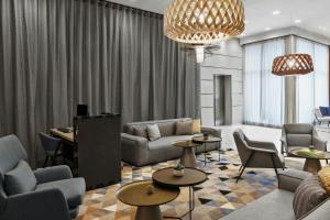 a living room with couches and tables and a chandelier at Courtyard by Marriott Munich City East in Munich