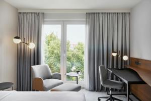 a hotel room with a bed and a desk and a window at Courtyard by Marriott Munich City East in Munich