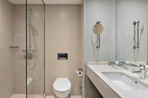 a bathroom with a shower and a toilet and a sink at Courtyard by Marriott Munich City East in Munich