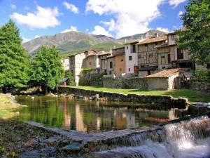 a town with a river and buildings and a waterfall at La Casita del Tejo in Hervás